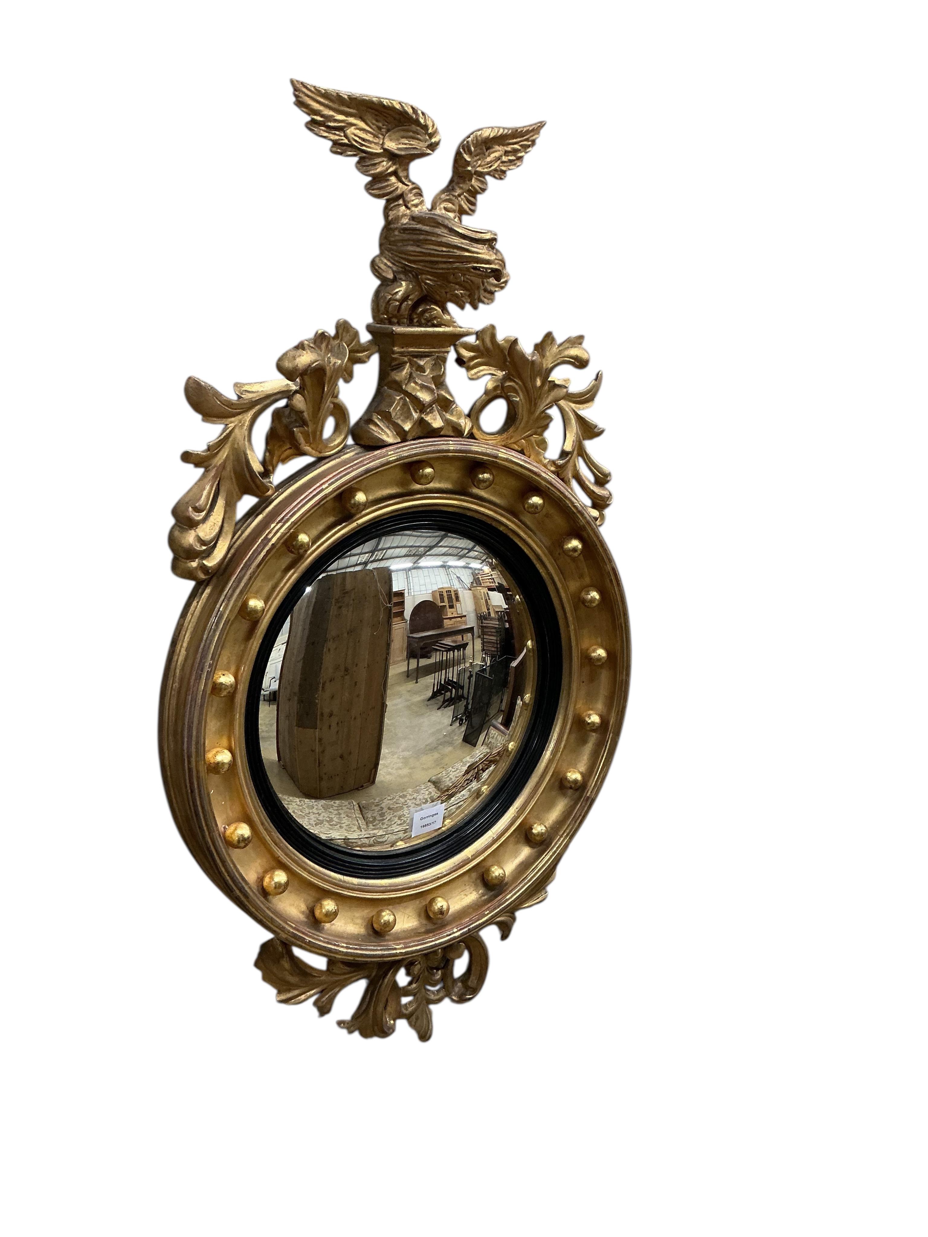 A Regency carved giltwood and composition convex wall mirror, with eagle surmount, width 54cm, height 96cm